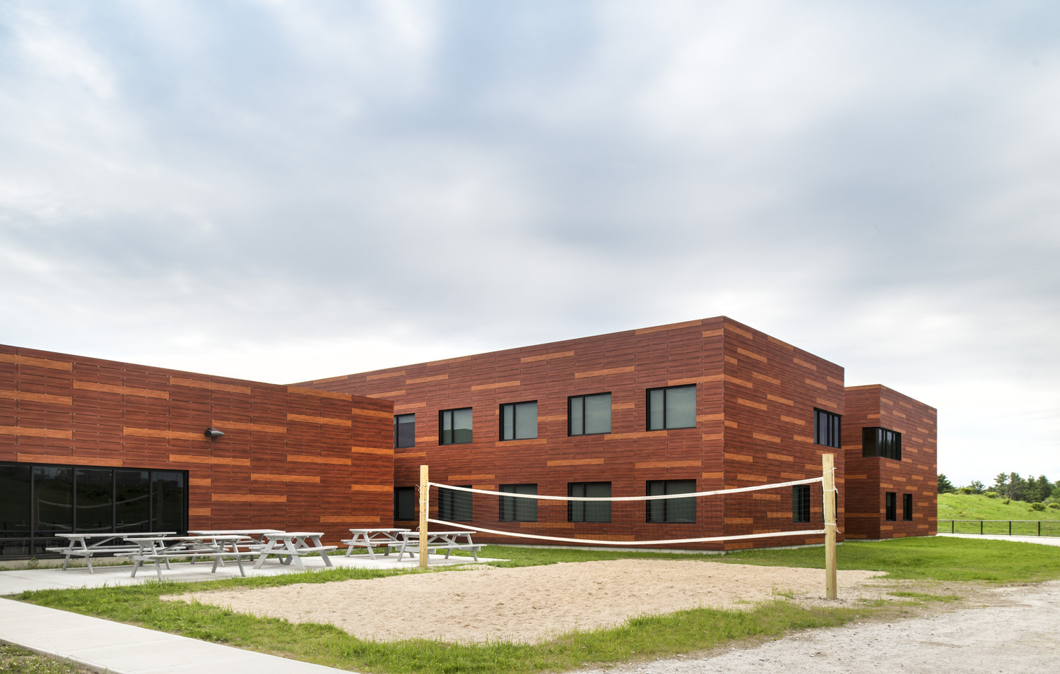 The outdoor space of the center includes a volleyball court and picnic tables.